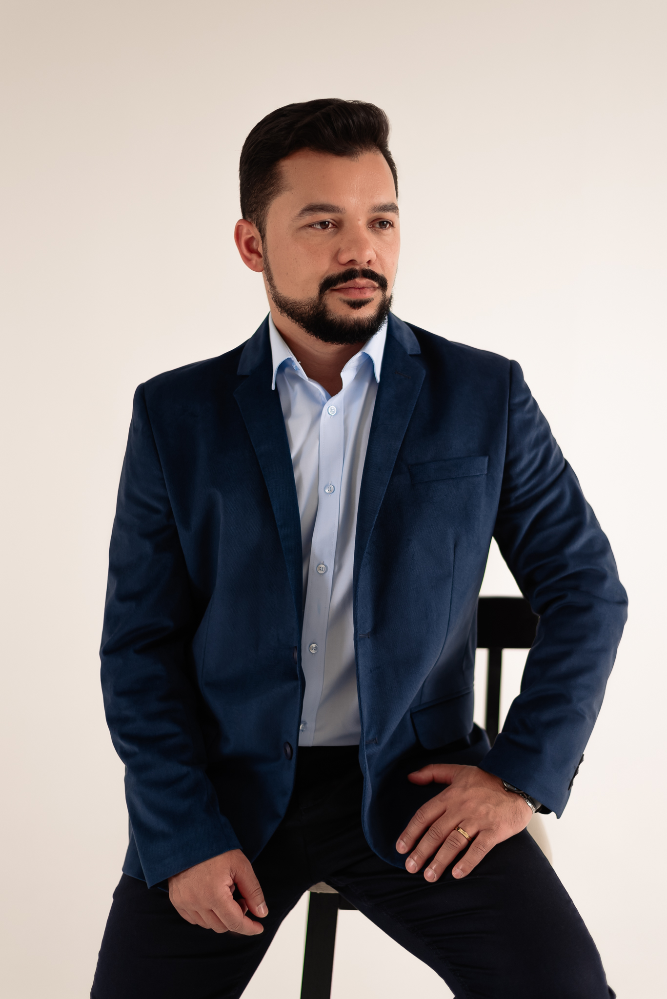 Louis Servilha sentado, de blazer azul, em retrato profissional